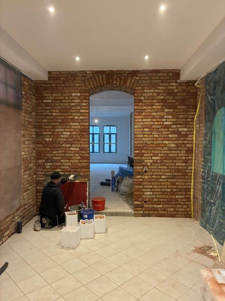 Blick in einen Raum mit geklinkerten Wänden und Renovierungsarbeiten im Gange.