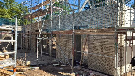 Baustelle mit Gerüst und Mauerwerksarbeiten an einem Gebäude.